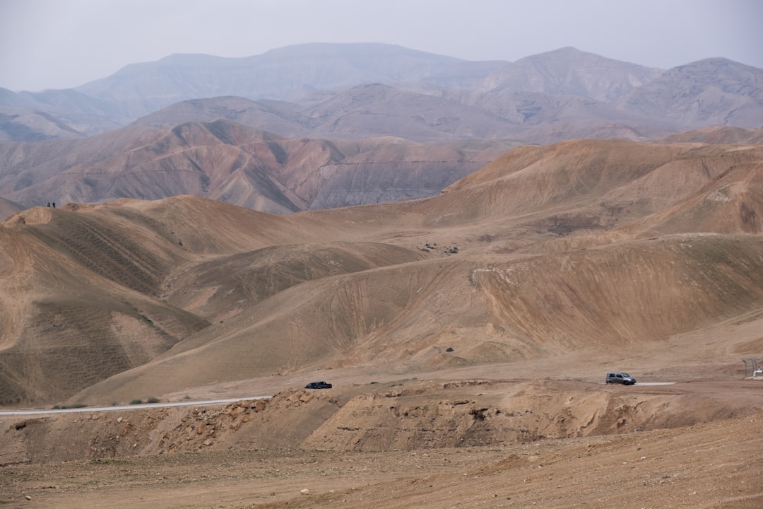 זוג מטייל בשביל מדברי עם תצורות סלע ייחודיות ונוף לים המלח ברקע, בשעות הבוקר.