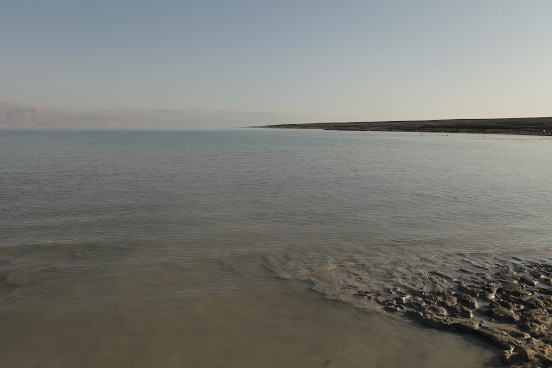 אנשים נהנים משחייה בים המלח ומריחת בוץ מינרלי בחוף פרטי, קרוב למתחם גלמפינג.