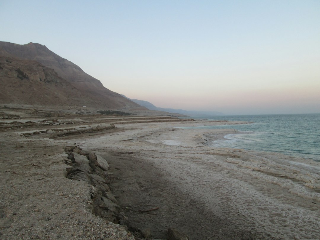 משפחה עם ילדים נהנית בחוף ים המלח, חאן קרוב נראה ברקע.