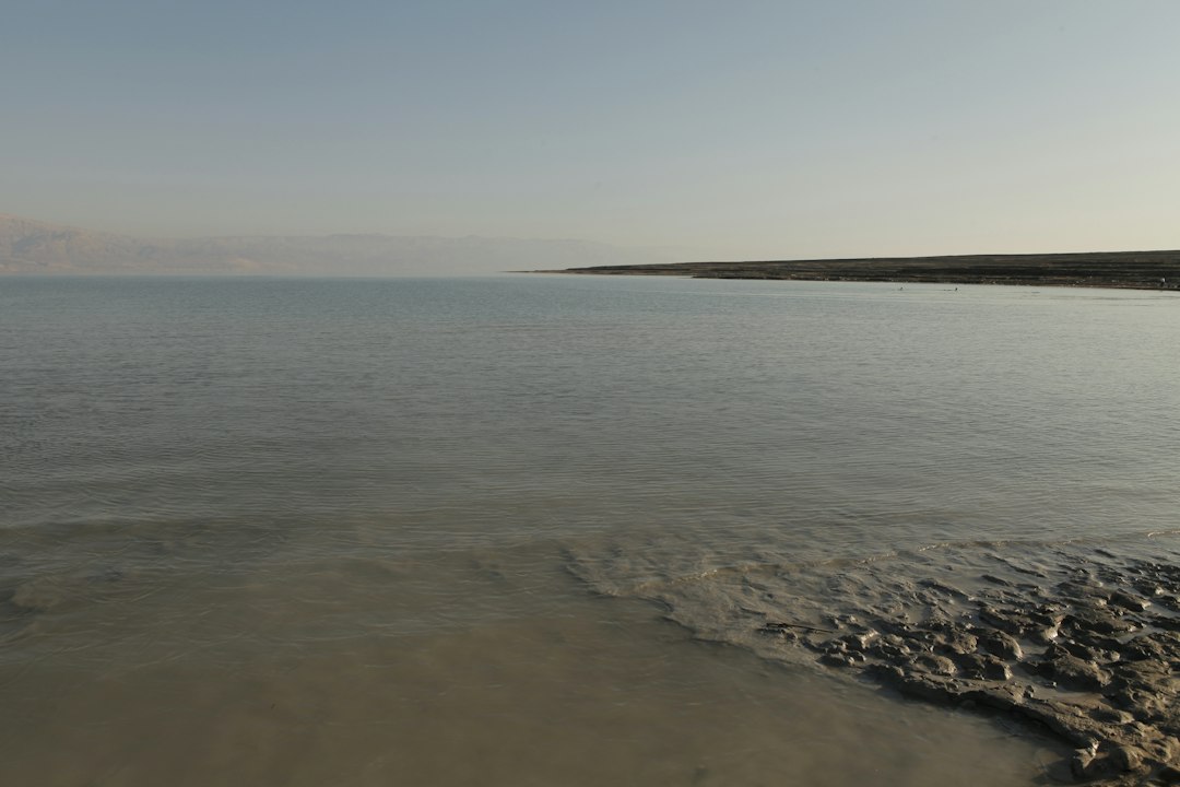 קבוצת מטיילים צופים בזריחה מעל נוף מדברי עוצר נשימה בים המלח, עם הרי המדבר ברקע.