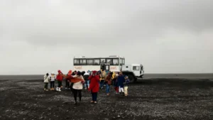 קבוצת מטיילים מודרכים מביטה אל תוך בולען גדול באזור ים המלח, עם נוף מדברי וים המלח ברקע.