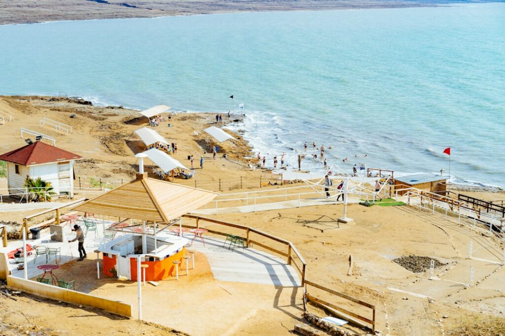 אוהל גלמפינג מרווח ומאובזר מול נוף ים המלח, עם מיטה נוחה ופינת ישיבה חיצונית.