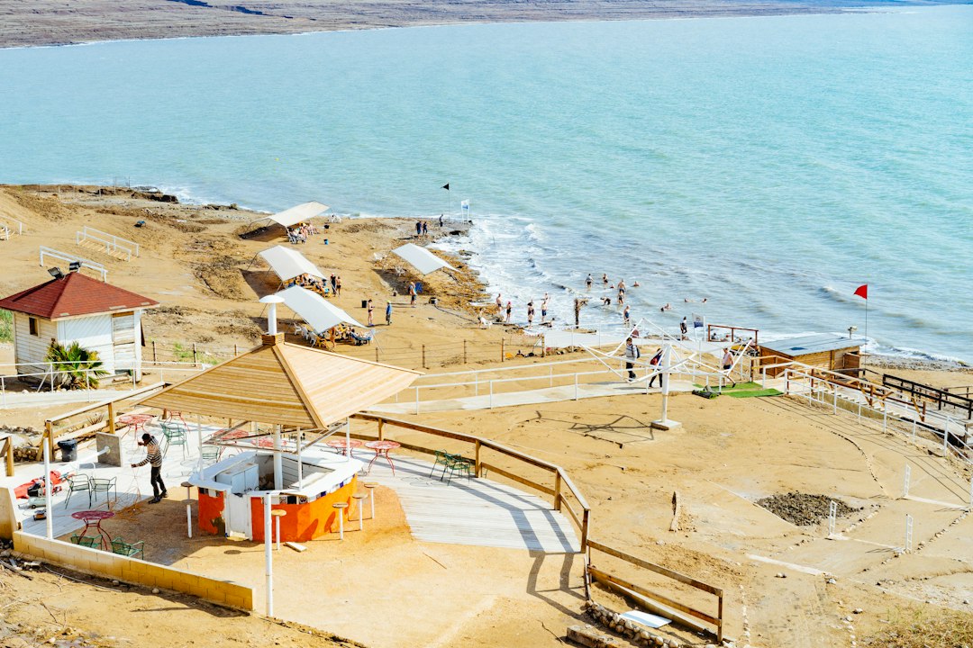 אוהל גלמפינג מרווח ומאובזר מול נוף ים המלח, עם מיטה נוחה ופינת ישיבה חיצונית.