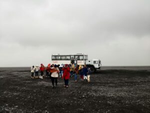 קבוצת מטיילים מודרכים מביטה אל תוך בולען גדול באזור ים המלח, עם נוף מדברי וים המלח ברקע.
