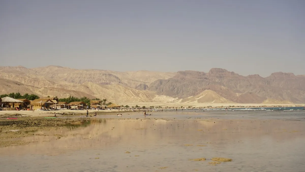 כפר נופש עם בקתות חוף וים המלח ברקע הרים מדבריים