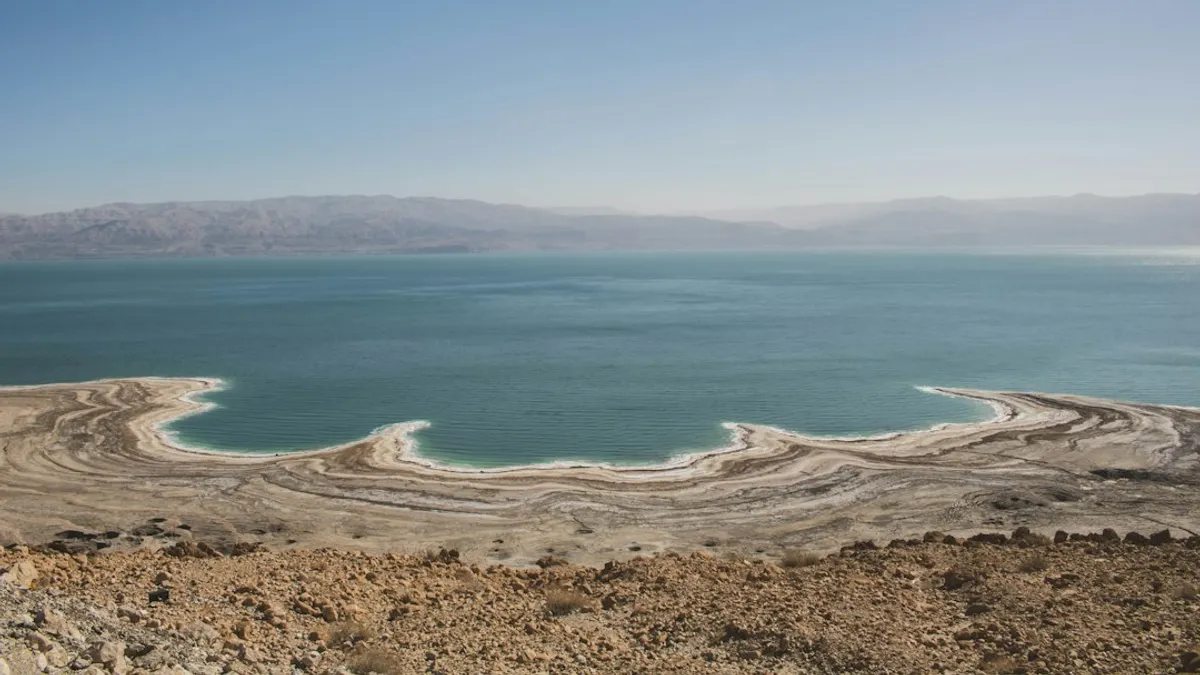 בור בולען עגול וברור בקרקע המדברית היבשה, עם שכבות אדמה גיאולוגיות חשופות סביבו.