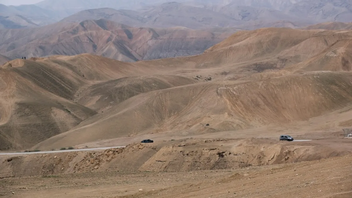 זוג מטייל בשביל מדברי עם תצורות סלע ייחודיות ונוף לים המלח ברקע, בשעות הבוקר. — גלמפינג ים המלח | תיירות קליה