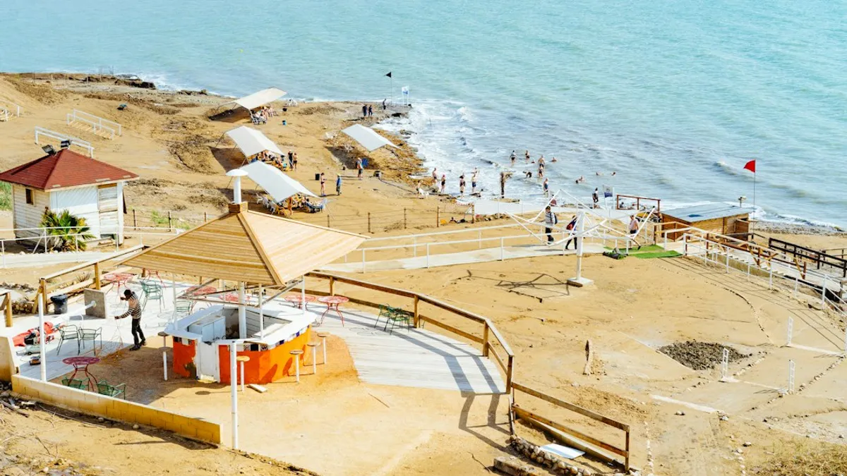 אוהל גלמפינג מרווח ומאובזר מול נוף ים המלח, עם מיטה נוחה ופינת ישיבה חיצונית.