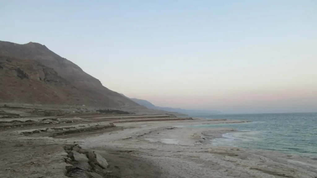 משפחה עם ילדים נהנית בחוף ים המלח, חאן קרוב נראה ברקע.