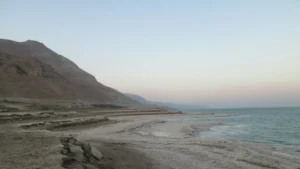 משפחה עם ילדים נהנית בחוף ים המלח, חאן קרוב נראה ברקע.